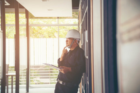 Man construction engineer writing note wear blue shirt safety white hard hat at construction site....