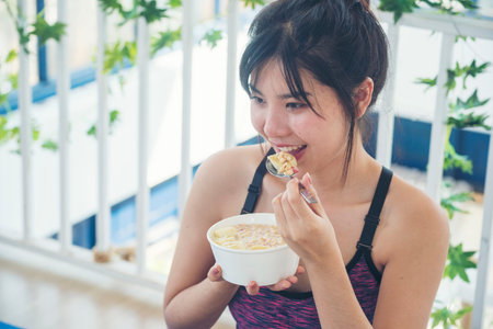 Asian women eating cereal oatmeal with milk organic nutrition ingredients. Women hands holding spoon...