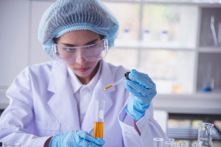 Scientist woman holding chemical test yellow glass tube testing science laboratory. Lab technician...