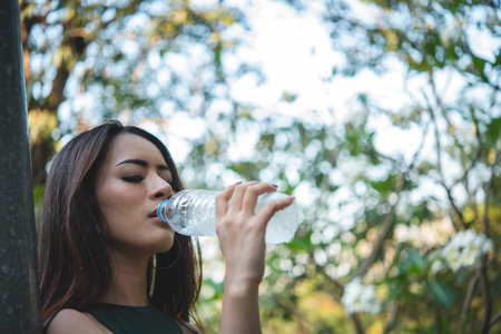 Young Woman Drinking Water bottle outdoor park traveler. Asian female drinking water bottle healthy...