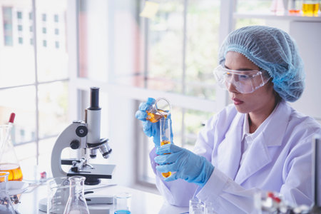 Scientist woman holding chemical test yellow glass tube testing science laboratory. Lab technician...