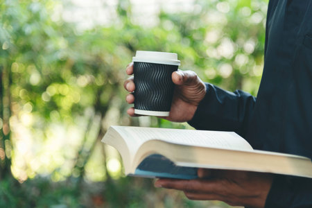 Asian man holding book reading magazine at green park in natural garden. Young man relaxation read...