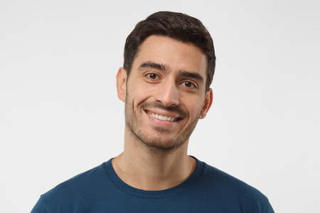 Close up shot of smiling attractive man in blue t-shirt isolated on gray backgroundの写真素材