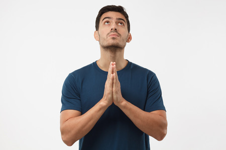 Religious young man pressing palms together, looking upwards, praying to god. Human emotions and feelings conceptの写真素材