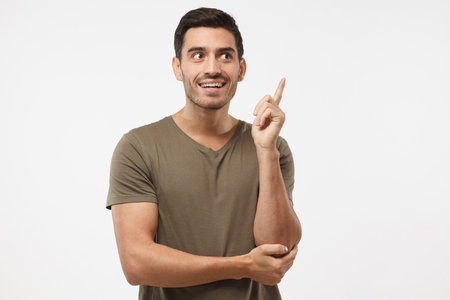 I have an idea! Close up shot of isolated on grey background man, pointing his finger in eureka sign, having great innovative idea, understanding solution he has just gotの写真素材