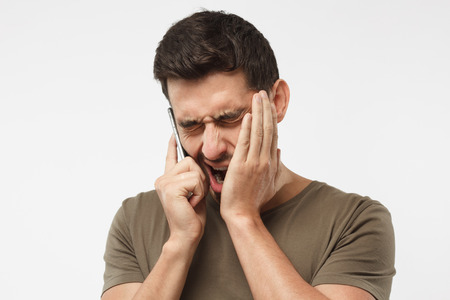 Close up portrait of bored guy, yawning because boring talk with boss, want to sleep, closing his mouth by hand, isolated on gray backgroundの写真素材