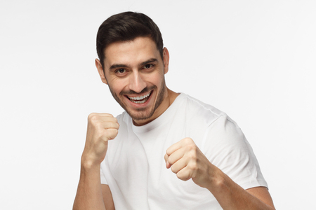 Close up portrait of smiling young man keeping his fists ready to fight and defense himself. Strong sporty man boxing, looking at camera with smileの写真素材