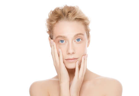 Young beautiful blonde blue eyed female with skin touching her face, isolated on whiteの写真素材