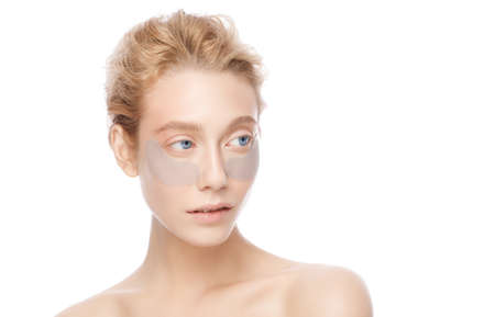 Beautiful girl standing with shoulders, wearing eye patches against dark circlesの写真素材
