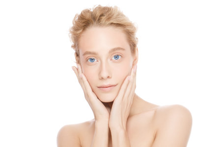 Beautiful model girl with perfect clean fresh skin touching her face isolated on white backgroundの写真素材