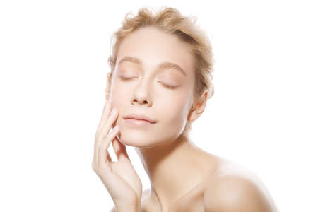Beauty portrait of young beautiful blonde woman face with closed eyes, touching her perfect skinの写真素材