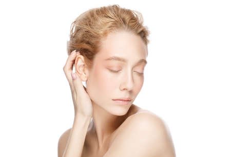 Beauty of young beautiful blond woman face, eyes closed, touching her perfect clean skinの写真素材