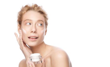 Banner of young beautiful woman with clear skin holding cosmetic jar and applying face creamの写真素材