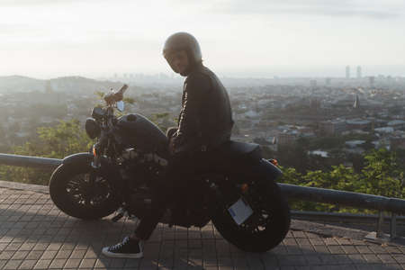 Biker or moto rider posing while doing his trip ride with beautiful city views