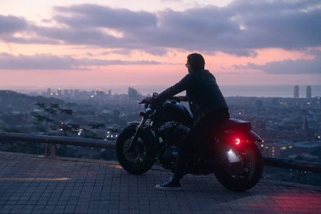Silhouette portrait of biker before sunrise, doing his trip ride with beautiful city viewsの写真素材
