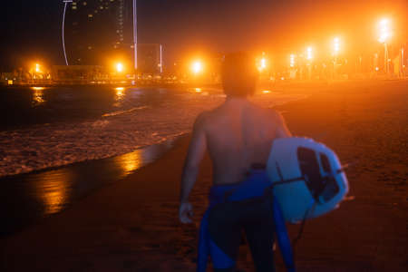 From the back silhouette shot of surfer holding surf board and looking awayの写真素材