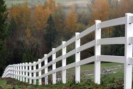 Scenic view of a white fencing heading down a hill during autumn season.の写真素材