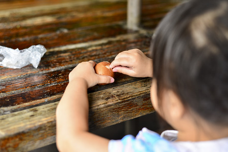 A little girl peeling a boiled eggの写真素材