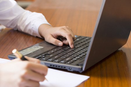 Young woman with a pen in front of the laptop to workのeditorial素材