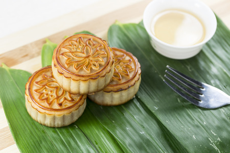 Stack of moon cakes, tea, fork on the background of bamboo leavesの写真素材