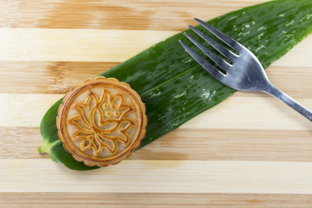 A mooncake, fork on the background of bamboo leavesの写真素材