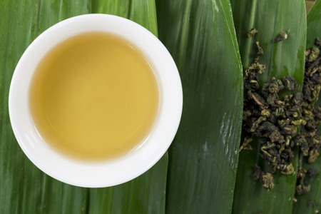 A cup of tea on the bamboo leaves on the tiled backgroundの写真素材