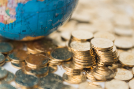 Stacked gold coins and globes backgroundの写真素材