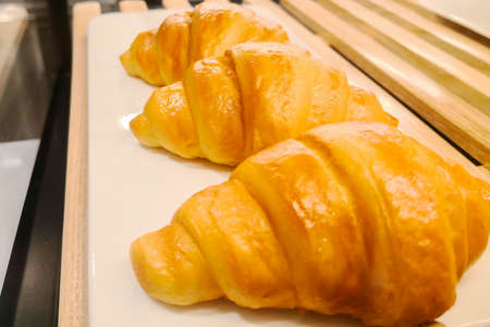 The delicious croissants are neatly arranged on white containers.