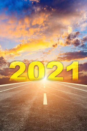 The 2021 numbers at sunrise are written on the road straight aheadの写真素材