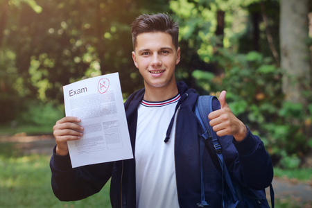 Portrait of a student showing the sheet of his exam in which he took a very high grade! Concept of: study, educational, school and university, and happiness.の写真素材