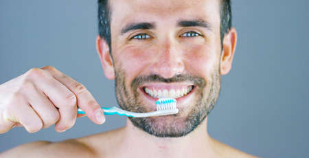 A beautiful portrait of a man smiles and shines his teeth showing his toothbrush and dentrifricio Concept: beauty, dentist, oral hygiene