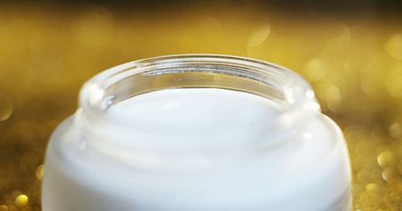 Beauty cream golden high quality for sensitive skin and rejuvenation, based on hyaluronidase acid isolated on a gold glitter background. concept of beauty and wealth in beauty creams for the skinの写真素材