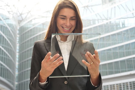 A woman in suits, uses a futuristic glass tablet. Concept of: future, technology, smartphone, augmented realityの写真素材
