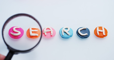 A magnifying glass hovers over the word &quot;love&quot; done in a creative and artistic as children. Concept of research, protected sites, creativity and colorの写真素材