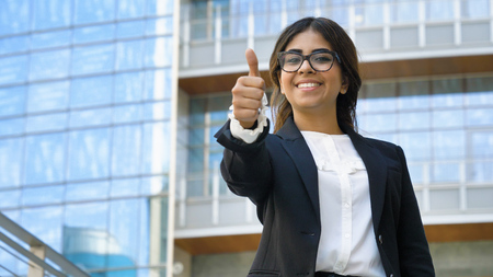 Portrait of young beautiful business woman (student) in suit, glasses, smiling, happy, walking down stairs, steps, on building background. Concept: new business, communication, Arab, banker, manager.の写真素材