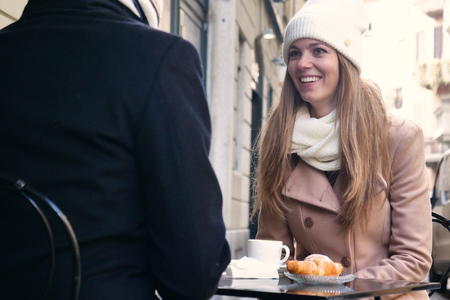 A couple of lovers have breakfast in a bar while sitting outdoors and looking at the phone. Concept of: love, valentine's day, technologyの写真素材