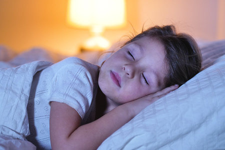 A little girl sleeps at night in her bedroom. Concept of: peaceful dreams, good sleep, relaxation, home.の写真素材