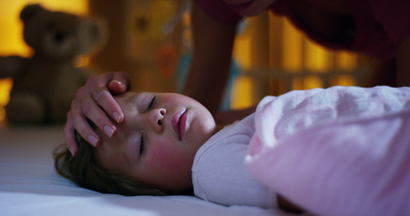 sleeping baby happy and carefree, the mother caresses kiss goodnight. concept of house and home. night and happy dreams, no mosquitoes, no noisy home and comfortable mattresses. comfortable childrenの写真素材