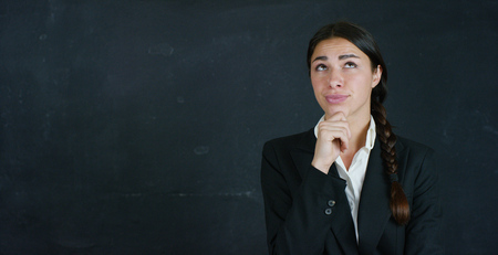 Portrait of a beautiful business girl, a marketing teacher, thinking about new ideas and strategies, on a black background. Concept: career growth, growth chart, successful girl, marketing, ideas.の写真素材