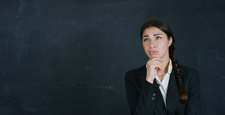 Portrait of a beautiful business girl, a marketing teacher, thinking about new ideas and strategies, on a black background. Concept: career growth, growth chart, successful girl, marketing, ideas.の写真素材