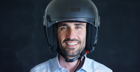 Portrait of a professional rider or motorcyclist, in a protective black helmet, on a black background. Concept: driver, drive, speed, defense, space, airplane, pilot, protective suit, extreme, sports.の写真素材