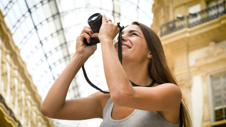 Milan, Italy. Beautiful young girl, woman in Milan, holding a photo camera, taking pictures, happy...