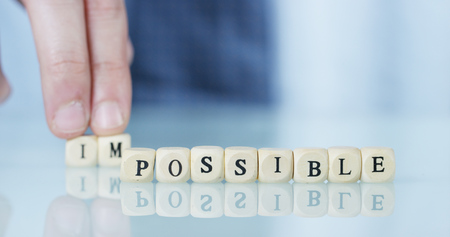 A hand turns the word "Impossible" to "Possible" throwing away the letters. Concept: commitment, believe it until the end, everything is possible.の写真素材