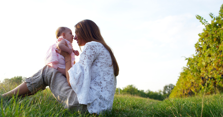 Portrait of young mother with her baby girl in pink on a meadow in vineyardの写真素材