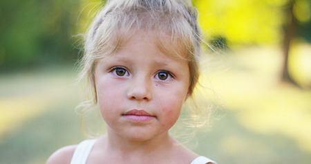 Close up of a shy innocent toddler looking at camera. Concept love of nature, protection of kids rights, sustainability, nature, purity and connection to green world.の写真素材