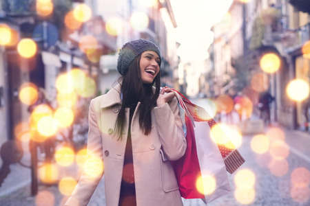 A beautiful girl smiles and is happy while shopping in the city. Concept of: shopping, holidays, happiness, christmas.の写真素材