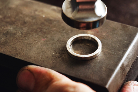 Close up of a goldsmith's hand making a gold or silver ring or a diamond using goldsmith's tools. For this work it takes precision and patience. Concept of: tradition, luxury, jewelry.の写真素材