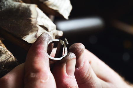 Close up of a goldsmith's hand making a gold or silver ring or a diamond using goldsmith's tools. For this work it takes precision and patience. Concept of: tradition, luxury, jewelry.の写真素材