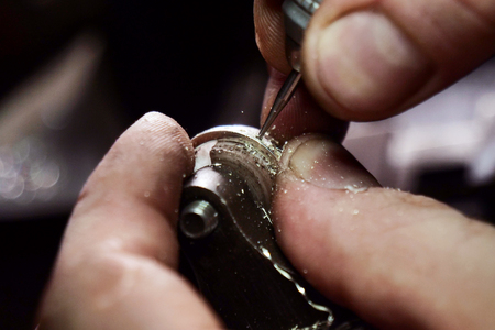 Close up of a goldsmith's hand making a gold or silver ring or a diamond using goldsmith's tools. For this work it takes precision and patience. Concept of: tradition, luxury, jewelry.の写真素材