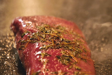 A chef, in a professional kitchen, cooks a tender tenderloin of meat in a professional pan. Concept of: cooking, chef, gourmet, italian foodの写真素材